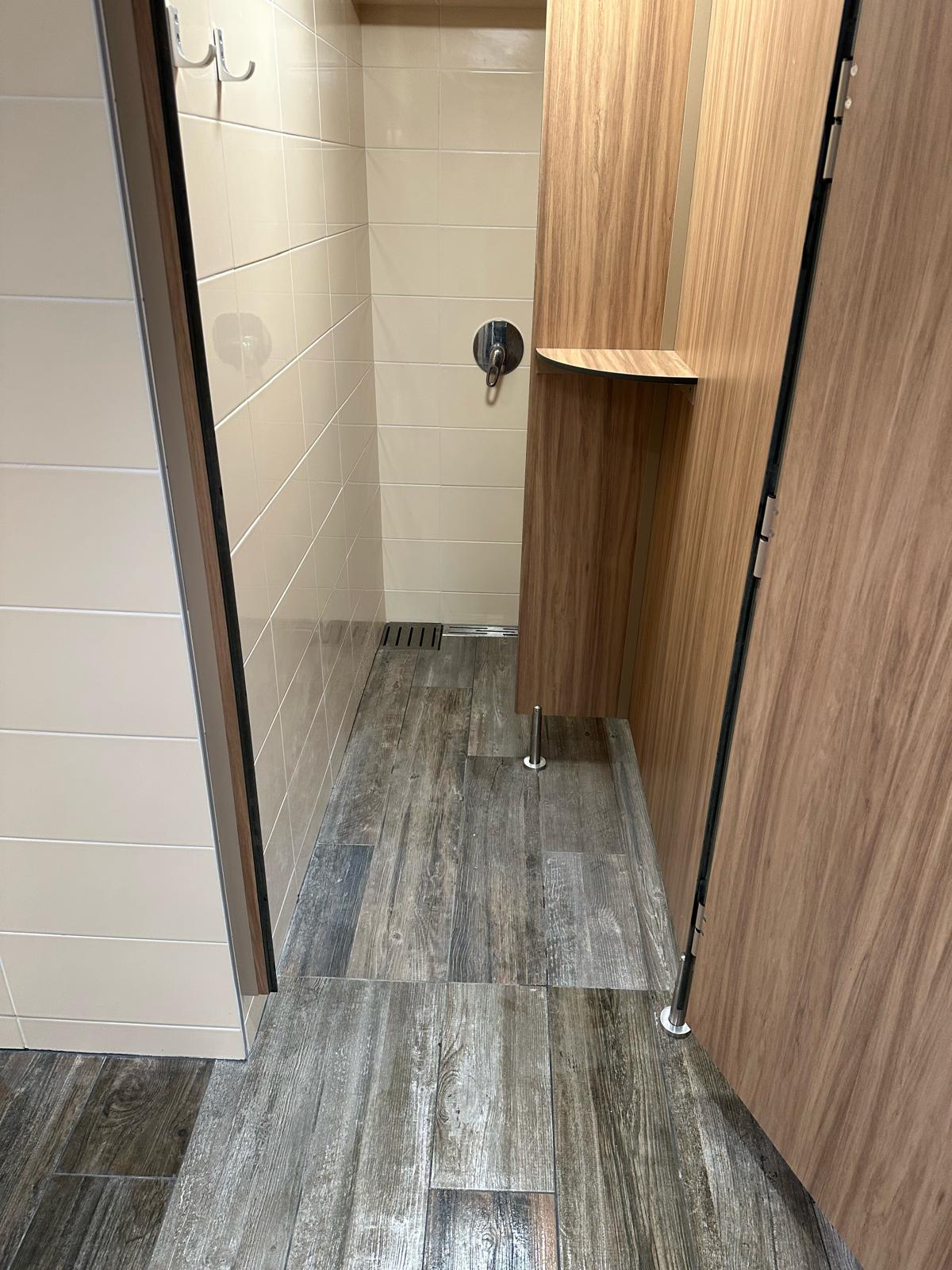 Cabine de douche rénovée avec faïence claire et caniveau de sol